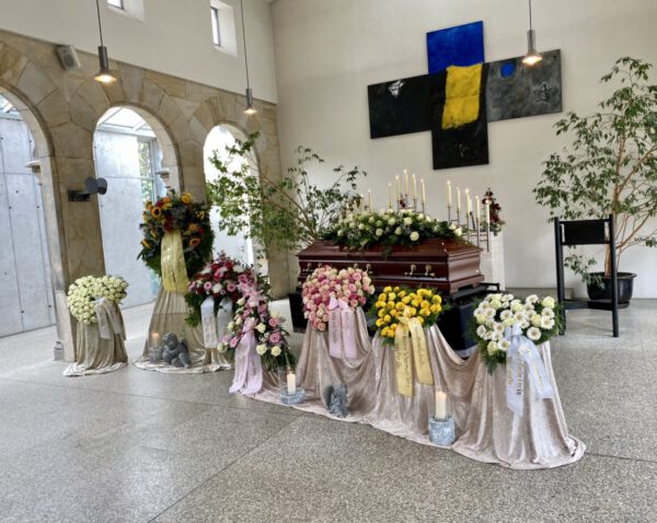 Verschiedene Blumenkränze und Blumenherzen bei einer Trauerfeier